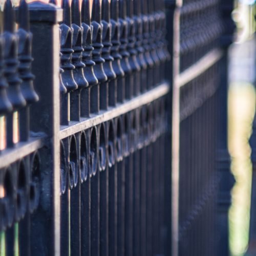 A vertical closeup shot of a metal fence on a sidewalk